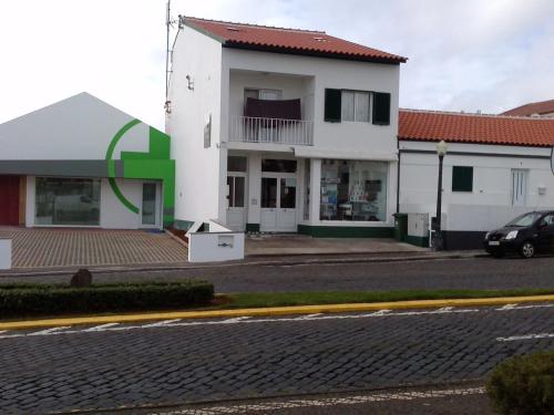 a white house with a red roof and a street at Apartamentos Lisboa in Vila do Porto