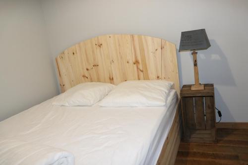 a bed with a wooden headboard and a table with a lamp at Appartement Barcelonnette centre in Barcelonnette