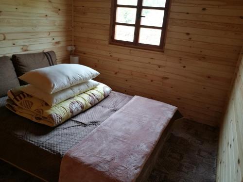 a log cabin with a bed with pillows on it at Nad Drawskim DOMKI LETNISKOWE in Czaplinek