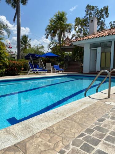 a swimming pool with a house and palm trees at Casa El Peñon in Girardot