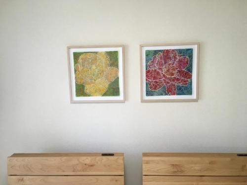 two framed pictures on a wall above a wooden dresser at Santari in Shintoku