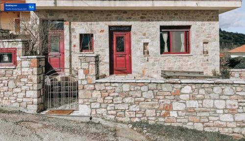 a stone house with red doors and a stone wall at studio Nick in Kalavrita