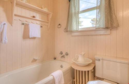 a white bathroom with a tub and a sink at Byers Boathouse on the Prom - Meredith Lodging in Seaside