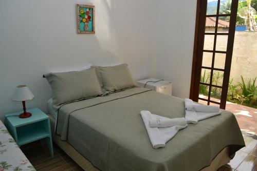 a bedroom with a bed with two towels on it at Pouso Paratiense Jabaquara in Paraty