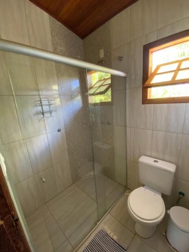 a bathroom with a toilet and a glass shower at Pousada Lapralapa in Santana do Riacho