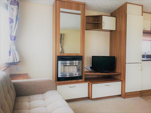 a living room with a couch and a television at Cypress Superior Holiday Home in Ingoldmells