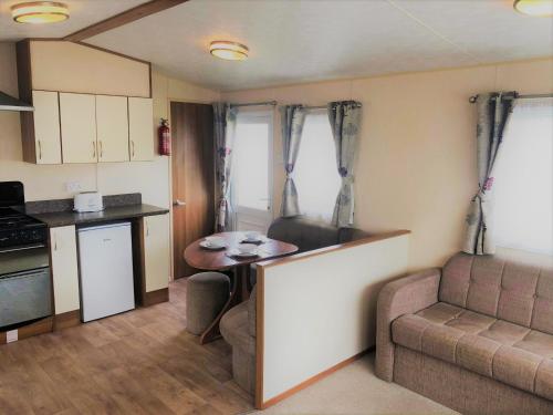 a kitchen and living room with a table and a couch at Cypress Superior Holiday Home in Ingoldmells