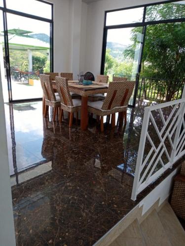 a wooden table and chairs in a room with windows at CASA EL MIRADOR in Anapoima