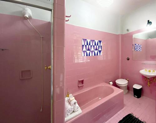 a pink bathroom with a tub and a sink at Suíte Exclusiva Charmosa com Varanda Verde - 100m da Paulista in Sao Paulo