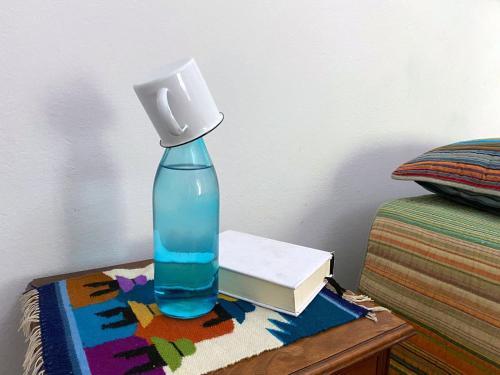 a blue bottle on a table next to a book at Suíte Exclusiva Charmosa com Varanda Verde - 100m da Paulista in Sao Paulo