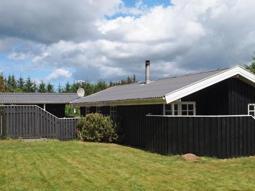 una casa negra con una valla al lado de un patio en 6 person holiday home in Blokhus en Blokhus