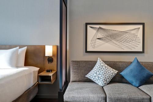 a bedroom with a bed and a couch with pillows at Hyatt Place Prince George in Prince George
