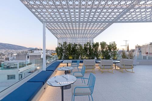 a rooftop patio with tables and chairs on a building at Acro Urban Suites in Athens