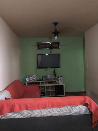 een woonkamer met een rode bank en een flatscreen-tv bij Flavia Aluguel Temporada in Cabo Frio