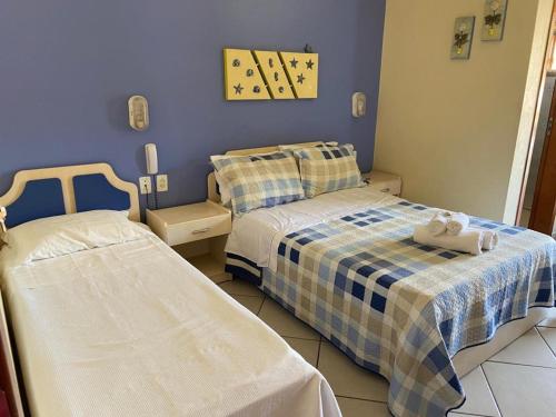 two beds in a room with blue walls at Pousada Maré Mar in Garopaba