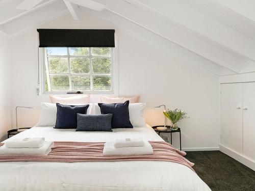 a white bedroom with a large bed with blue pillows at Whisky Creek in Berrima