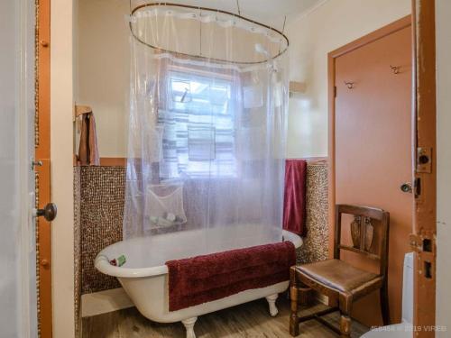 a bath tub in a bathroom with a chair at Woods End Landing in Bamfield