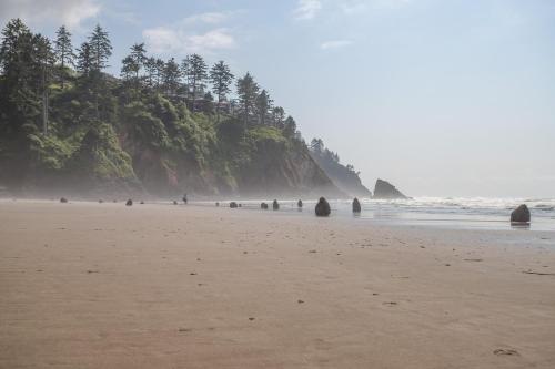 a beach with a group of people standing on the sand at Valhalla Vista - Meredith Lodging in Neskowin