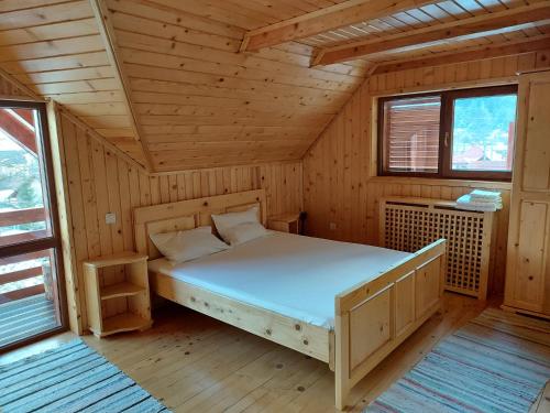 ein Schlafzimmer mit einem Bett in einem Holzzimmer in der Unterkunft Modern mountain village chalet in Carpathians in Lereşti