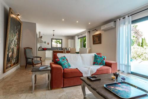 a living room with a red couch and a table at La Verdière - Contemporary house with garden and private pool in LʼIsle-sur-la-Sorgue