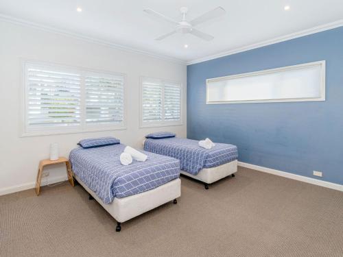 2 Betten in einem Zimmer mit blauen Wänden und Fenstern in der Unterkunft Seagrass House in Yamba