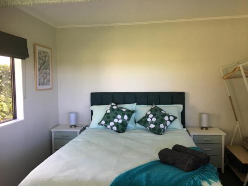 1 dormitorio con 1 cama con almohadas blancas y negras en Te Harinui - Peaceful rural escape, en Tauranga