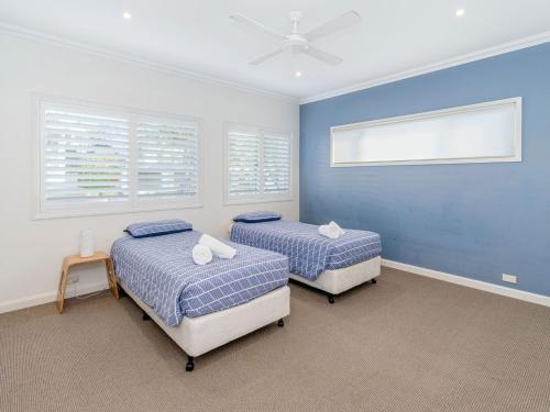 Duas camas num quarto com paredes e janelas azuis em Seagrass Unit 1 em Yamba