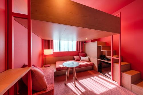 a red room with a bunk bed and a table at toggle hotel suidobashi TOKYO in Tokyo