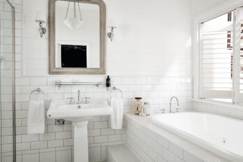 a white bathroom with a tub and a sink at The Blackwood Sassafras in Sassafras