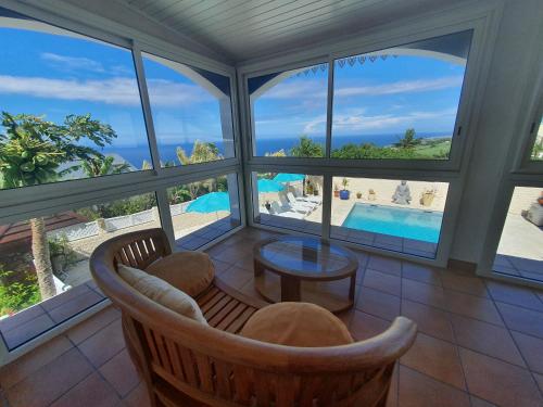 a living room with a view of the pool and the ocean at VILLA Tsara in Petite Île