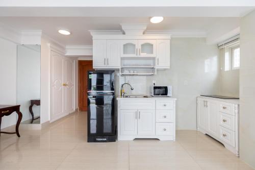 a kitchen with white cabinets and a black refrigerator at Homestay coco in Vung Tau