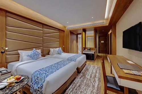 Dormitorio con cama, escritorio y TV en The Fern Leo Resort & Club - Junagadh, Gujarat en Jūnāgadh