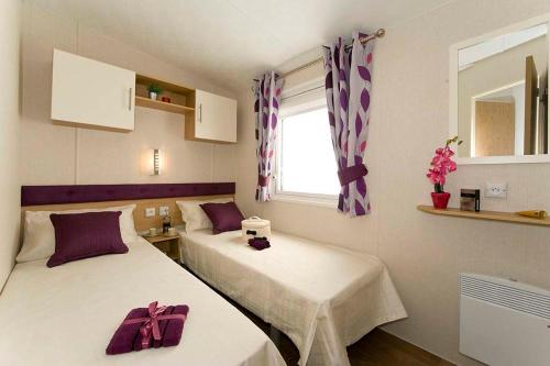 2 bedden in een kleine kamer met paarse bogen bij Camping Les Lacs de Courtès in Estang
