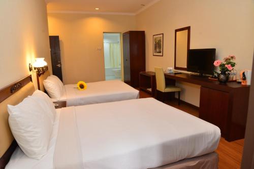 a hotel room with two beds and a desk with a computer at Cheng Ho Hotel in Malacca