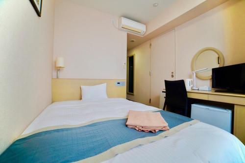 a bedroom with a large white bed and a desk at Hotel Frontier Iwaki in Iwaki