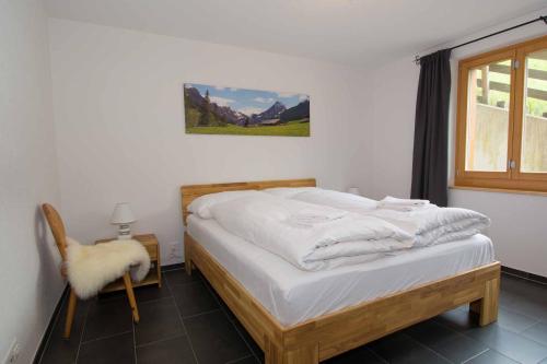 a bedroom with a bed and a chair and a window at Schützenrain 1. Stock in Adelboden