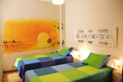 two beds in a room with a painting on the wall at La Pintada in Valladolid