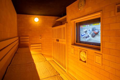 a room with a tv on a brick wall at Dormy Inn Premium Nagasaki Ekimae in Nagasaki