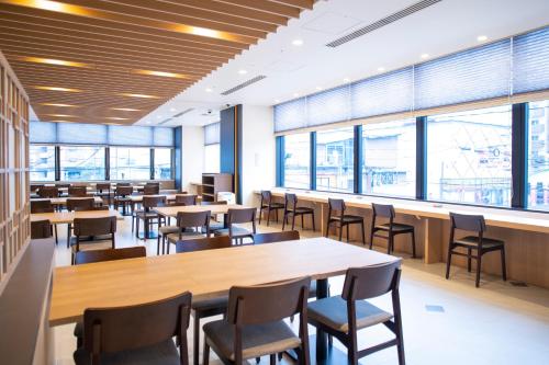 a cafeteria with tables and chairs and windows at Dormy Inn Premium Nagasaki Ekimae in Nagasaki