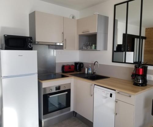 une cuisine avec des armoires blanches et un réfrigérateur blanc dans l'établissement Magnifique Vue Centre Station, à Les Deux Alpes