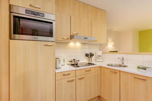 a kitchen with wooden cabinets and a sink at Center Parcs Sauerland Winterberg-Medebach in Medebach