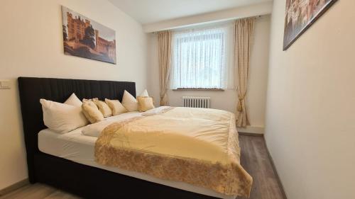 1 dormitorio con 1 cama con cabecero negro y ventana en City Apartment Alici, en Füssen