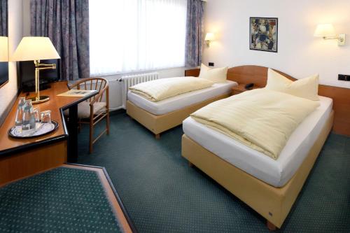 a hotel room with two beds and a desk at LAT Hotel & Apartmenthaus Berlin in Eisenhüttenstadt