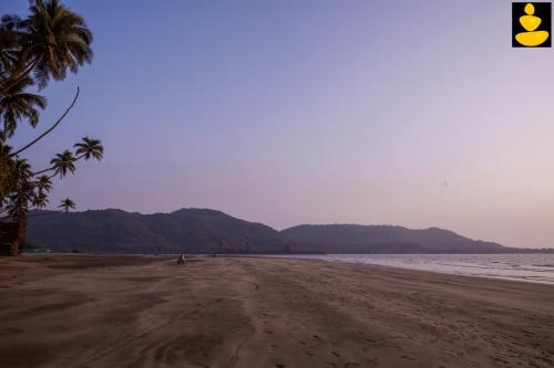 an empty beach with palm trees and the ocean at LivingStone 3BHK Beach House Alibaug in Alibaug
