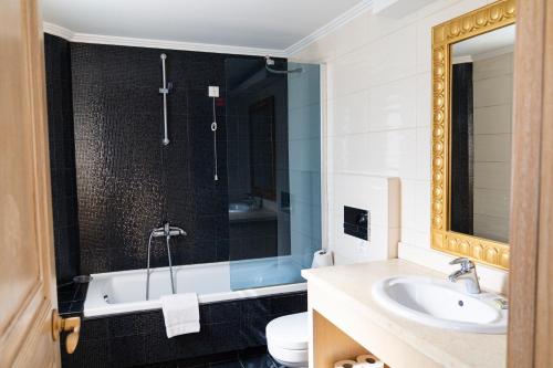 a bathroom with a tub and a sink and a toilet at Okeanis Golden Resort in Kato Daratso