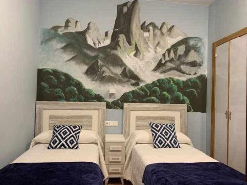 una camera con due letti e un dipinto sul muro di Cumbres de los Picos Apartamento Urriellu a Poo de Cabrales