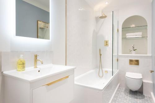 Baño blanco con lavabo y aseo en Brunswick Patio Apartment, en Brighton & Hove