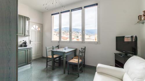 a living room with a table and chairs and a tv at Italianway - Roma 70 in Sanremo