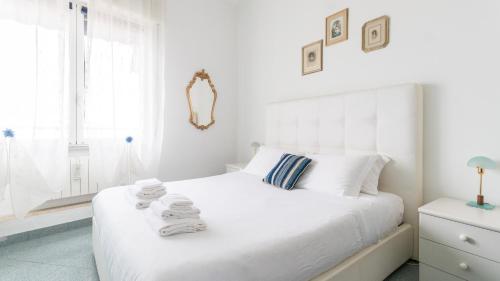 a white bedroom with a large bed with towels on it at Italianway - Roma 70 in Sanremo