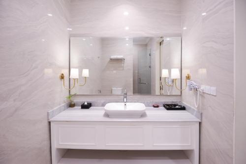 a white bathroom with a sink and a mirror at Grand Senyum Hotel, Tugu Yogyakarta in Yogyakarta
